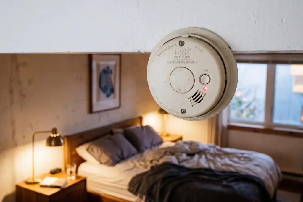 Smoke detector in a modern vacation rental bedroom suggesting hidden surveillance concerns