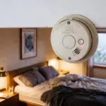Smoke detector in a modern vacation rental bedroom suggesting hidden surveillance concerns