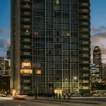 Historic Atlanta high-rise condominium building at dusk with a mix of lit and dark windows representing the divide between residents and short-term rental investors