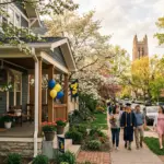 Charming college town residential street during graduation weekend with families walking past craftsman houses and a university campus in the background