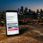 Smartphone showing high Airbnb nightly price with Kansas City skyline in background