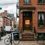 City code enforcement officer in front of a short-term rental property with a notice posted on the door in an urban American neighborhood